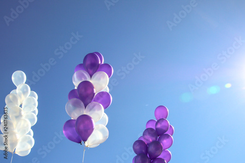 White and purple balloons on the sky background