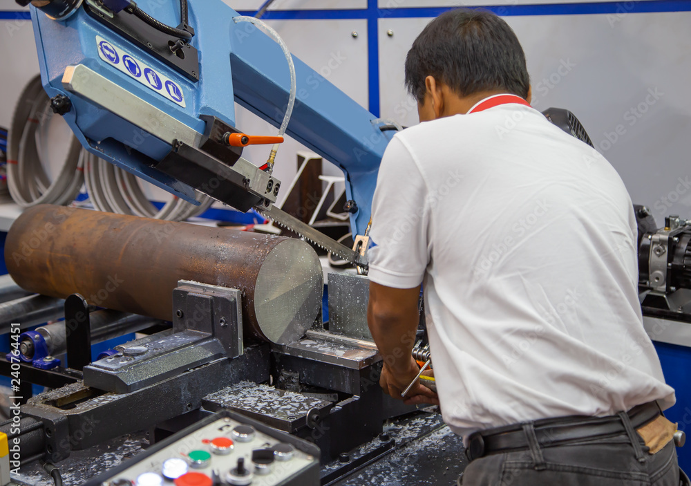 Industrial technician operate band saw machine cutting metal work piece with coolant. Industrial metalworking machinery Industrial technician operate band saw machine cutting metal work piece with coolant. Industrial metalworking machinery
