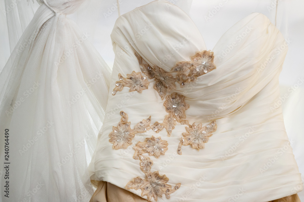 Details of the bride's white and gold wedding dress hanging on a four poster bed Details of the bride's white and gold wedding dress hanging on a four poster bed