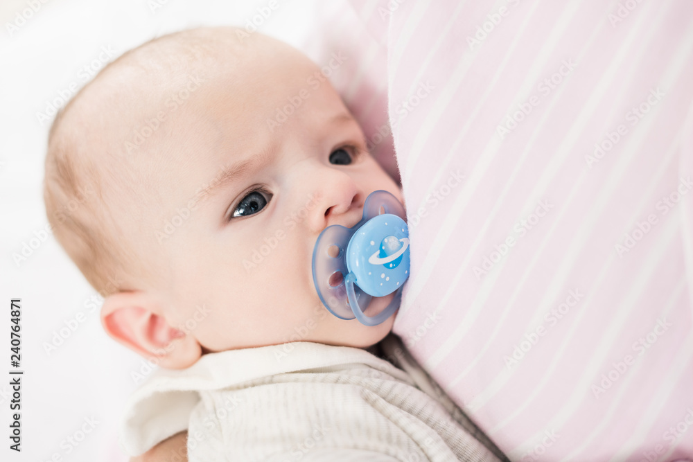 partial view of little baby with pacifier on mothers hands partial view of little baby with pacifier on mothers hands