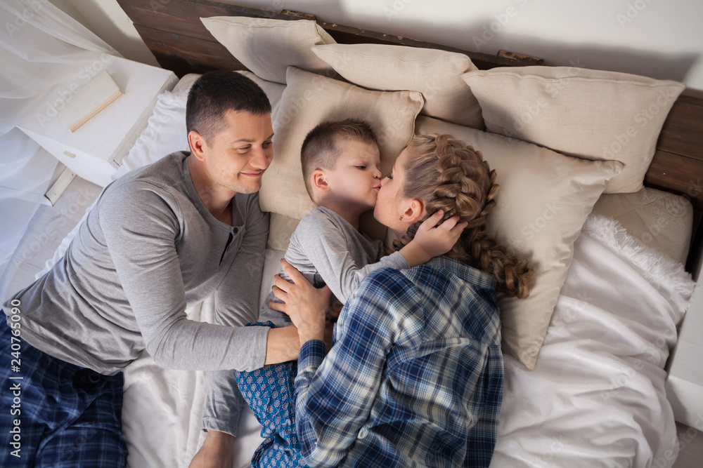 mom dad and young son sleep on the bed in the bedroom