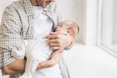 cropped shot of father holding little sleeping son in hands