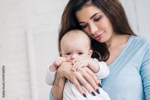 portrait of young mother with little baby in hands at home