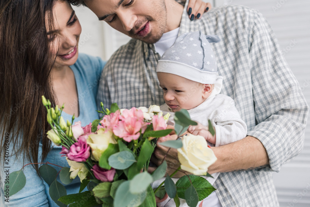 portrait of happy parents with little son and bouquet of flowers at home portrait of happy parents with little son and bouquet of flowers at home