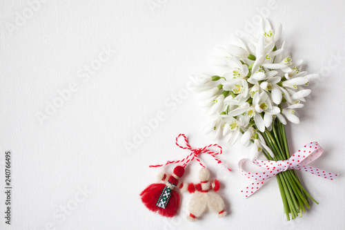 Fototapeta Naklejka Na Ścianę i Meble -   A bouquet of snowdrops on a white canvas and a red-white martenitsa, a symbol of the holiday on March 1, Martisor, Baba Marta.