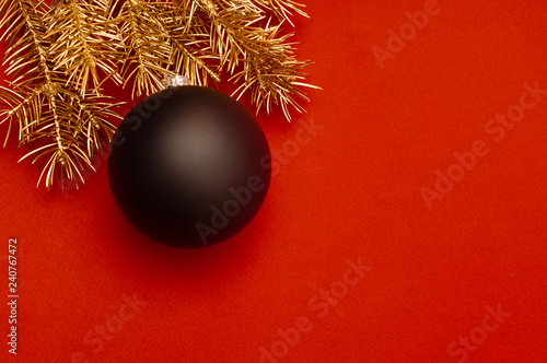 Creative pattern with golden Christmas tree branches and big black bauble.