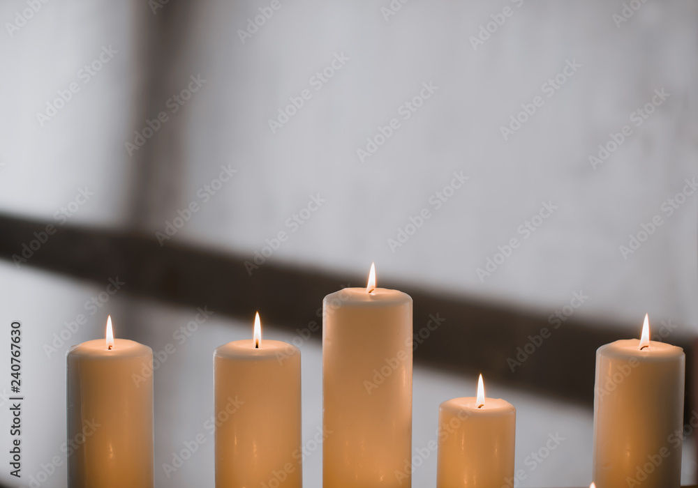 A group of different sized candles stands on a simple wooden table. A group of different sized candles stands on a simple wooden table.