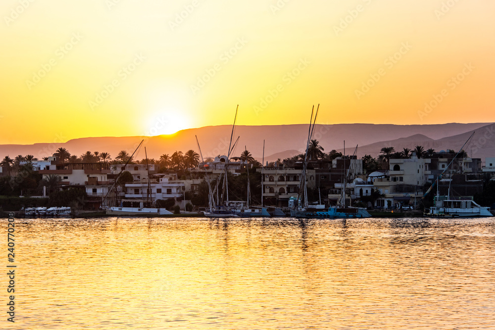 View of the Nile river with sailboats at golden colorful sunset in Luxor, Egypt