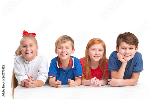 Full length portrait of cute little kids girls and boys in stylish clothes looking at camera and smiling against white studio wall. Kids fashion concept