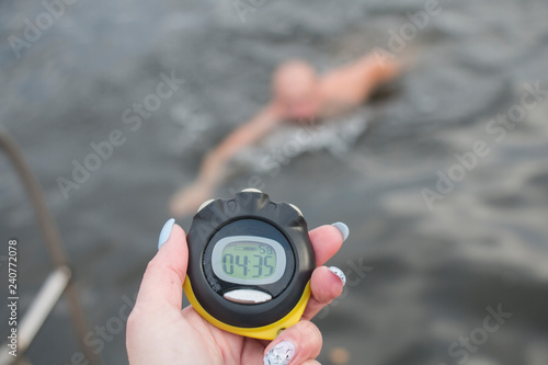 Swimming coach looking at a stopwatch in open water extreme swimming