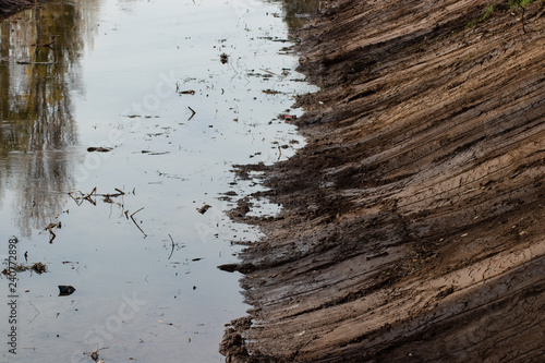 muddy berm beside river water