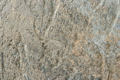The texture of a light gray stone with beige patches and a rough and matte surface. Grunge background with space for text or image. Gray backdrop.