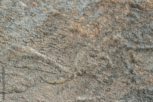 The texture of a light gray stone with beige patches and a rough and matte surface. Grunge background with space for text or image. Gray backdrop.