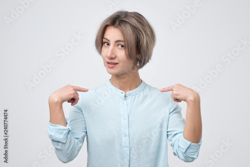 Wallpaper Mural Pretty young woman in blue shirt pointing at herself in confusion isolated on white background. Will you select me concept Torontodigital.ca