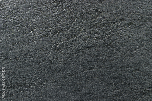 The texture of a dark gray stone with a rough and matte surface. Grunge background with space for text or image. Empty template and mockup for designers.