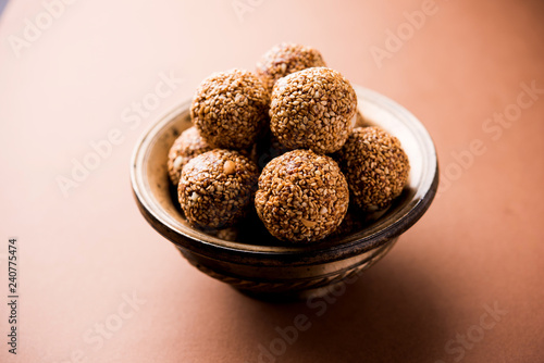 Tilgul Laddu or Til Gul balls for makar sankranti, it's a healthy food made using sesame, crushed peanuts and jaggery. served in a bowl. selective focus showing details.