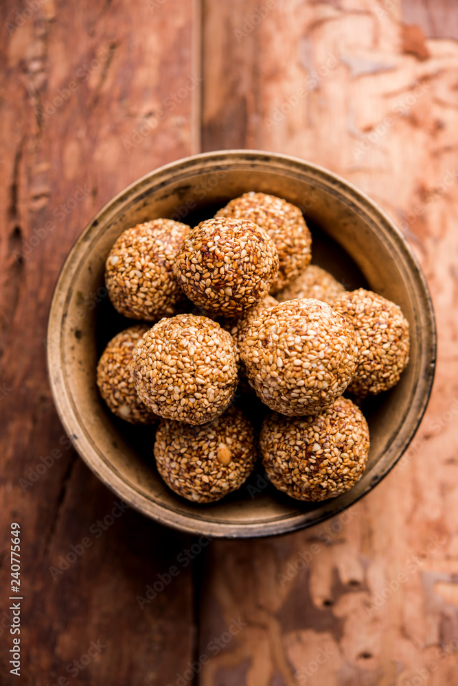 Tilgul Laddu or Til Gul balls for makar sankranti, it's a healthy food made using sesame, crushed peanuts and jaggery. served in a bowl. selective focus showing details. Tilgul Laddu or Til Gul balls for makar sankranti, it's a healthy food made using sesame, crushed peanuts and jaggery. served in a bowl. selective focus showing details.