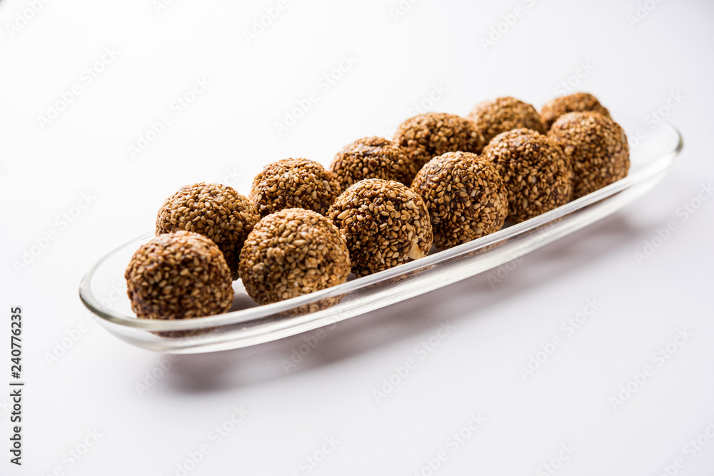 Tilgul Laddu or Til Gul balls for makar sankranti, it's a healthy food made using sesame, crushed peanuts and jaggery. served in a bowl. selective focus showing details. Tilgul Laddu or Til Gul balls for makar sankranti, it's a healthy food made using sesame, crushed peanuts and jaggery. served in a bowl. selective focus showing details.