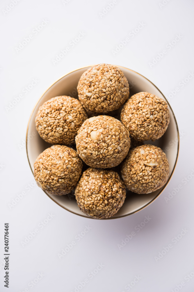 Tilgul Laddu or Til Gul balls for makar sankranti, it's a healthy food made using sesame, crushed peanuts and jaggery. served in a bowl. selective focus showing details. Tilgul Laddu or Til Gul balls for makar sankranti, it's a healthy food made using sesame, crushed peanuts and jaggery. served in a bowl. selective focus showing details.