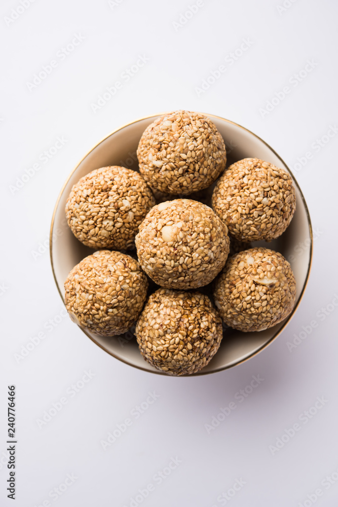 Tilgul Laddu or Til Gul balls for makar sankranti, it's a healthy food made using sesame, crushed peanuts and jaggery. served in a bowl. selective focus showing details. Tilgul Laddu or Til Gul balls for makar sankranti, it's a healthy food made using sesame, crushed peanuts and jaggery. served in a bowl. selective focus showing details.