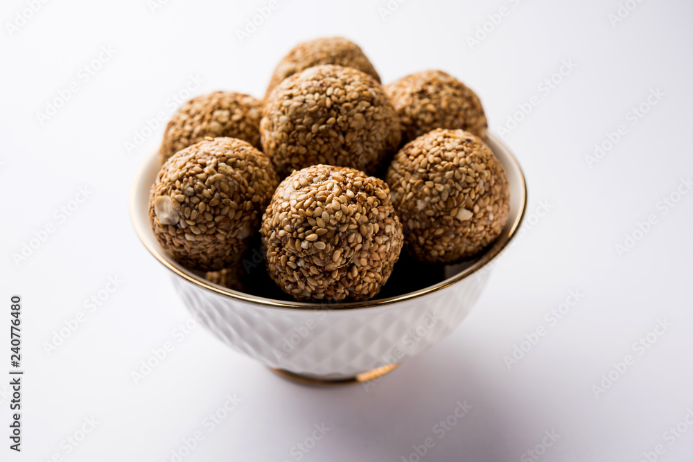 Tilgul Laddu or Til Gul balls for makar sankranti, it's a healthy food made using sesame, crushed peanuts and jaggery. served in a bowl. selective focus showing details. Tilgul Laddu or Til Gul balls for makar sankranti, it's a healthy food made using sesame, crushed peanuts and jaggery. served in a bowl. selective focus showing details.