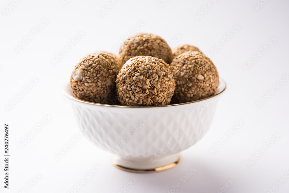 Tilgul Laddu or Til Gul balls for makar sankranti, it's a healthy food made using sesame, crushed peanuts and jaggery. served in a bowl. selective focus showing details. Tilgul Laddu or Til Gul balls for makar sankranti, it's a healthy food made using sesame, crushed peanuts and jaggery. served in a bowl. selective focus showing details.