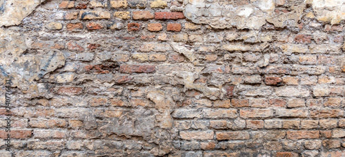 Old vintage dirty brick wall with peeling plaster texture background