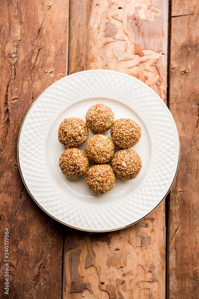 Tilgul Laddu or Til Gul balls for makar sankranti, it's a healthy food made using sesame, crushed peanuts and jaggery. served in a bowl. selective focus showing details. Tilgul Laddu or Til Gul balls for makar sankranti, it's a healthy food made using sesame, crushed peanuts and jaggery. served in a bowl. selective focus showing details.
