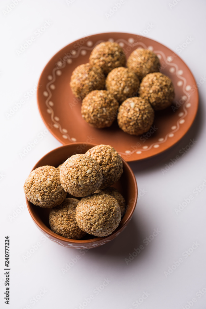 Tilgul Laddu or Til Gul balls for makar sankranti, it's a healthy food made using sesame, crushed peanuts and jaggery. served in a bowl. selective focus showing details. Tilgul Laddu or Til Gul balls for makar sankranti, it's a healthy food made using sesame, crushed peanuts and jaggery. served in a bowl. selective focus showing details.