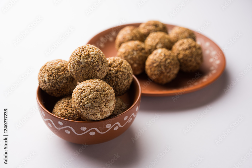 Tilgul Laddu or Til Gul balls for makar sankranti, it's a healthy food made using sesame, crushed peanuts and jaggery. served in a bowl. selective focus showing details. Tilgul Laddu or Til Gul balls for makar sankranti, it's a healthy food made using sesame, crushed peanuts and jaggery. served in a bowl. selective focus showing details.