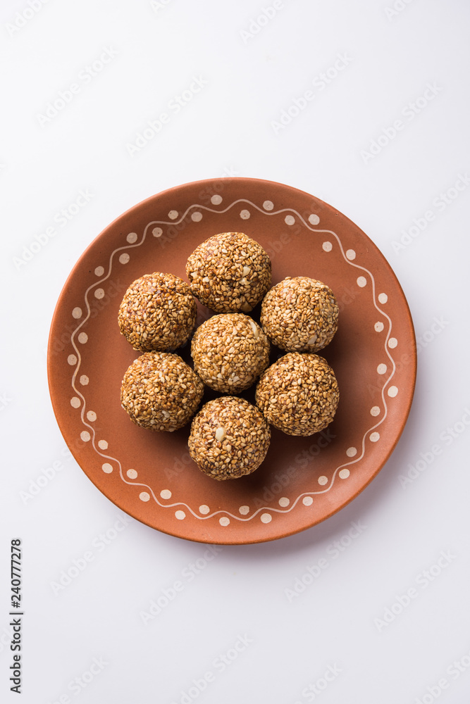 Tilgul Laddu or Til Gul balls for makar sankranti, it's a healthy food made using sesame, crushed peanuts and jaggery. served in a bowl. selective focus showing details. Tilgul Laddu or Til Gul balls for makar sankranti, it's a healthy food made using sesame, crushed peanuts and jaggery. served in a bowl. selective focus showing details.