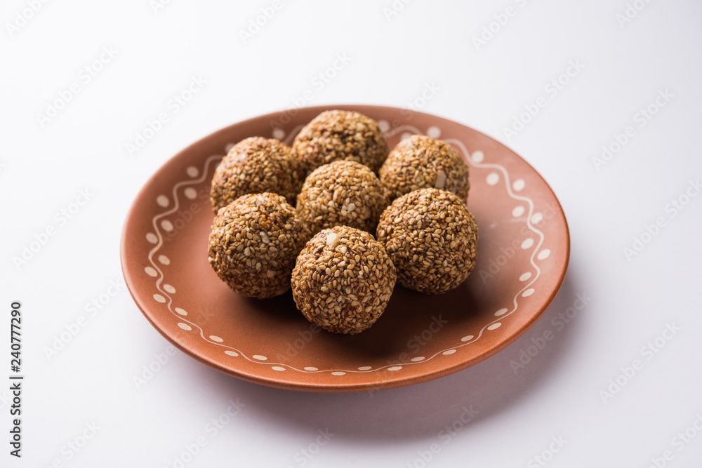 Tilgul Laddu or Til Gul balls for makar sankranti, it's a healthy food made using sesame, crushed peanuts and jaggery. served in a bowl. selective focus showing details. Tilgul Laddu or Til Gul balls for makar sankranti, it's a healthy food made using sesame, crushed peanuts and jaggery. served in a bowl. selective focus showing details.