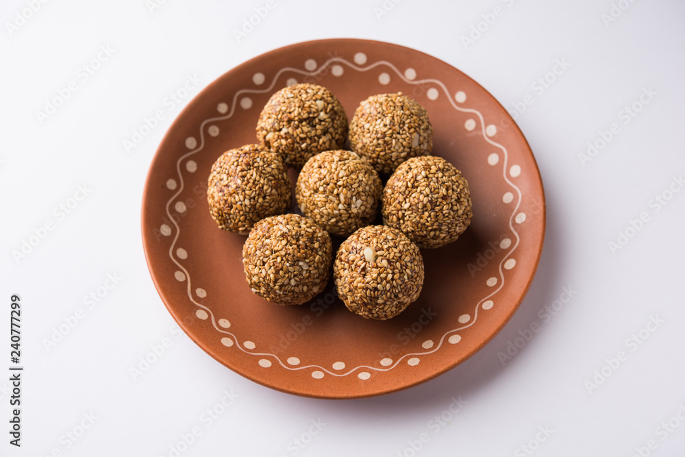 Tilgul Laddu or Til Gul balls for makar sankranti, it's a healthy food made using sesame, crushed peanuts and jaggery. served in a bowl. selective focus showing details. Tilgul Laddu or Til Gul balls for makar sankranti, it's a healthy food made using sesame, crushed peanuts and jaggery. served in a bowl. selective focus showing details.
