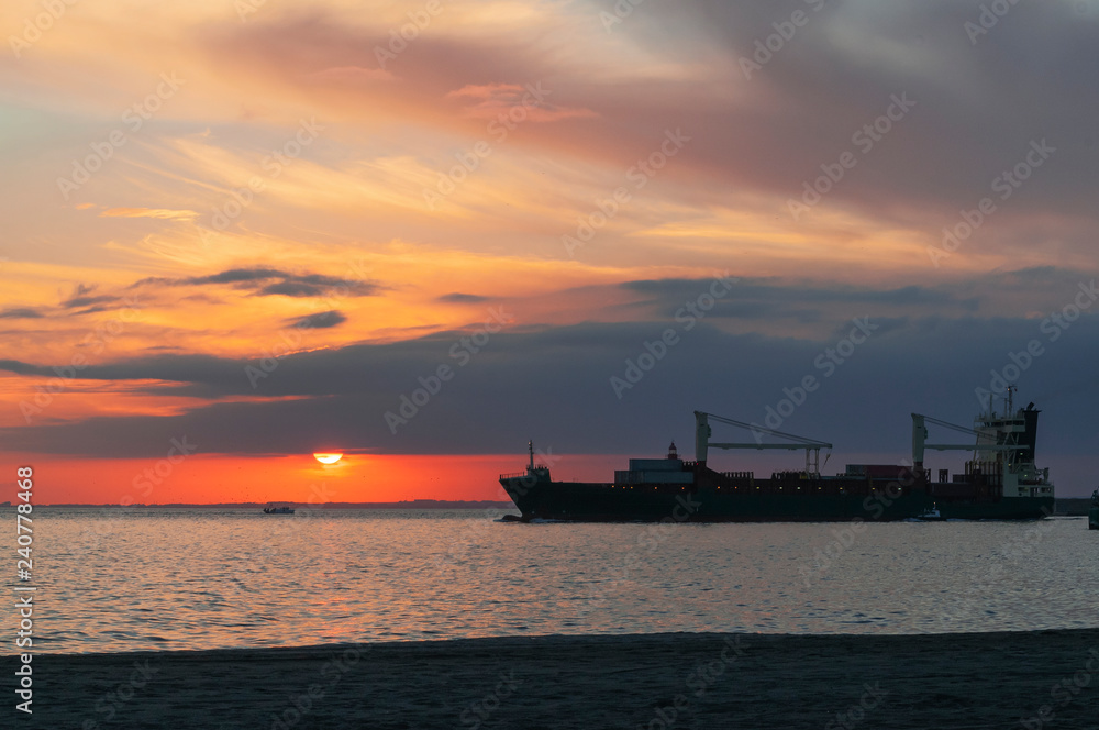 Carguero saliendo del puerto en la puesta de sol