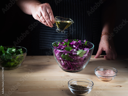 Obraz na plátně Chef pouring sunflower-seed oil on red cabbage salad, cooking process