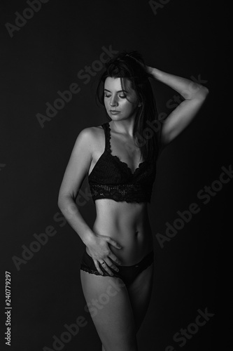 Sexy body of young attractive woman. Beautiful sporty lady in black bikini against dark background © nata_zhekova