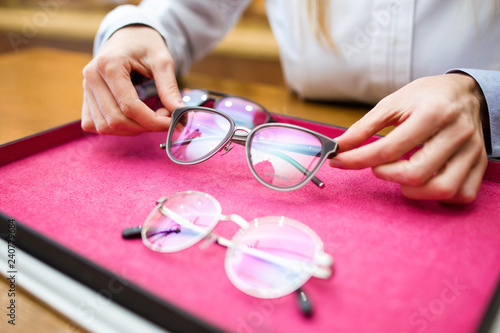 Ophthalmologist hands showing eyeglasses to customer in optic shop. photo