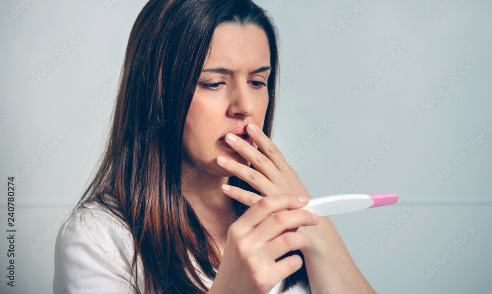 Worried pregnant woman looking at a pregnancy test Worried pregnant woman looking at a pregnancy test