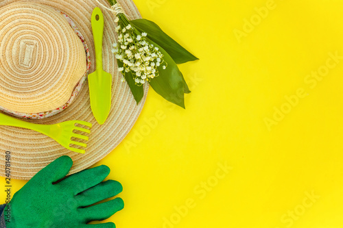 Flat Lay gardening tools, hat, shovel, rake, glove, flowers on yellow colourful trendy background. Spring or summer in garden, eco, nature, farm, horticulture hobby concept photo