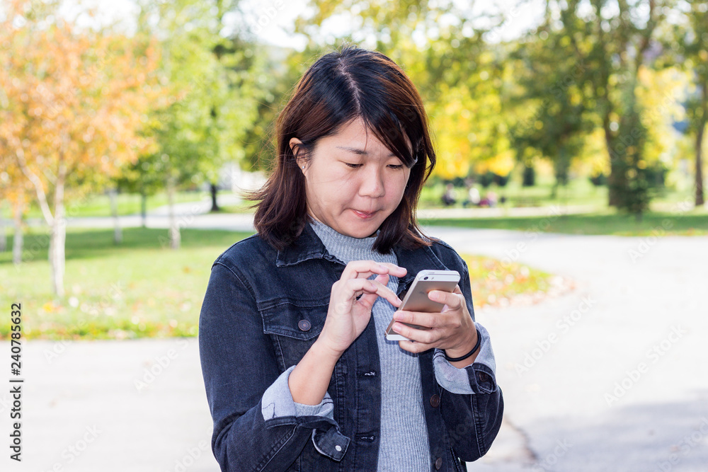 Close Up of Chinese Girl Using Cellphone in a Park