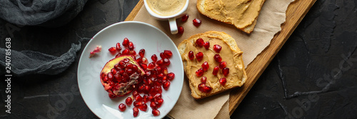 Sandwich with peanut paste and pomegranate grain red - breakfast or sweet snack (dessert). Top view. copy space