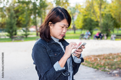 Close Up of Chinese Girl Using Cellphone in a Park