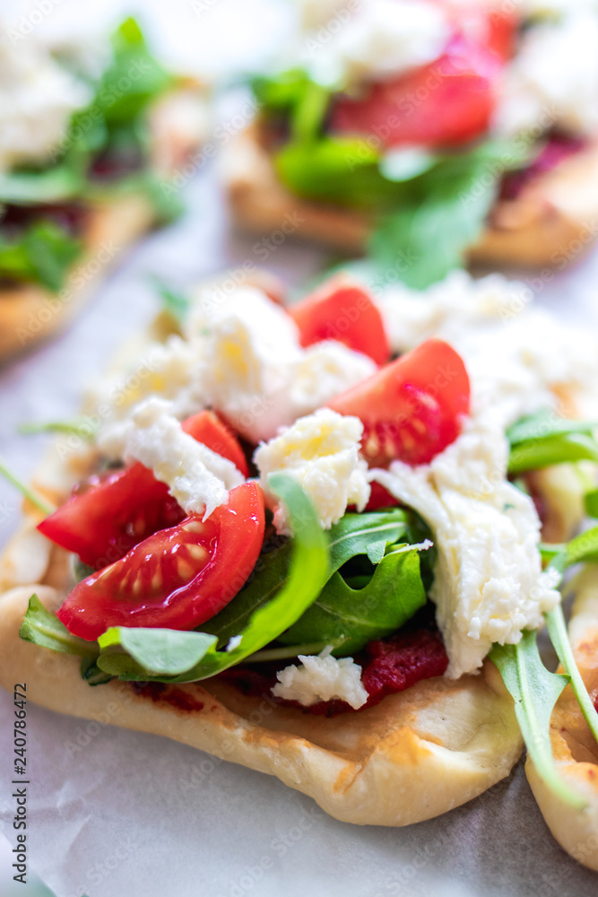 Mini pizza bites as appetizers, puff pastry as a base, topped with tomato puree, mozzarella and fresh ruccola.