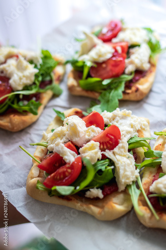 Mini pizza bites as appetizers, puff pastry as a base, topped with tomato puree, mozzarella and fresh ruccola.