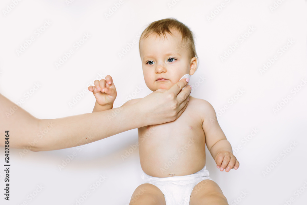Young mom wiping the baby skin body and face with wet wipes carefully on white background. concept cleaning wipe, pure, clean Young mom wiping the baby skin body and face with wet wipes carefully on white background. concept cleaning wipe, pure, clean