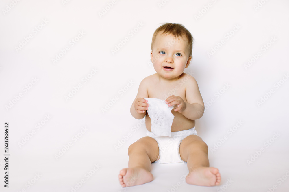 Charming happy little baby girl in white diaper holding wet wipe in her hands and sitting isolated on white background. Cleaning wipe, pure, clean Charming happy little baby girl in white diaper holding wet wipe in her hands and sitting isolated on white background. Cleaning wipe, pure, clean