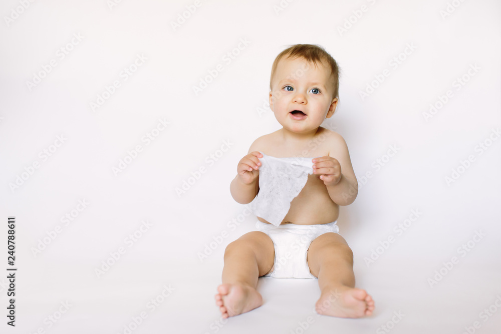 Charming happy little baby girl in white diaper holding wet wipe in her hands and sitting isolated on white background. Cleaning wipe, pure, clean Charming happy little baby girl in white diaper holding wet wipe in her hands and sitting isolated on white background. Cleaning wipe, pure, clean