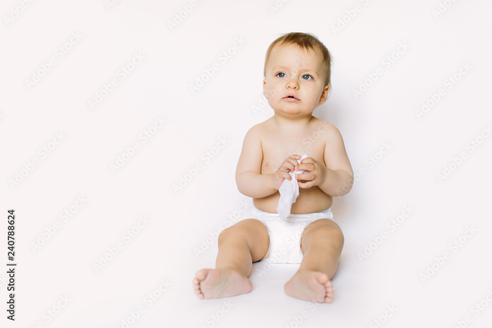 Charming happy little baby girl in white diaper holding wet wipe in her hands and sitting isolated on white background. Cleaning wipe, pure, clean Charming happy little baby girl in white diaper holding wet wipe in her hands and sitting isolated on white background. Cleaning wipe, pure, clean