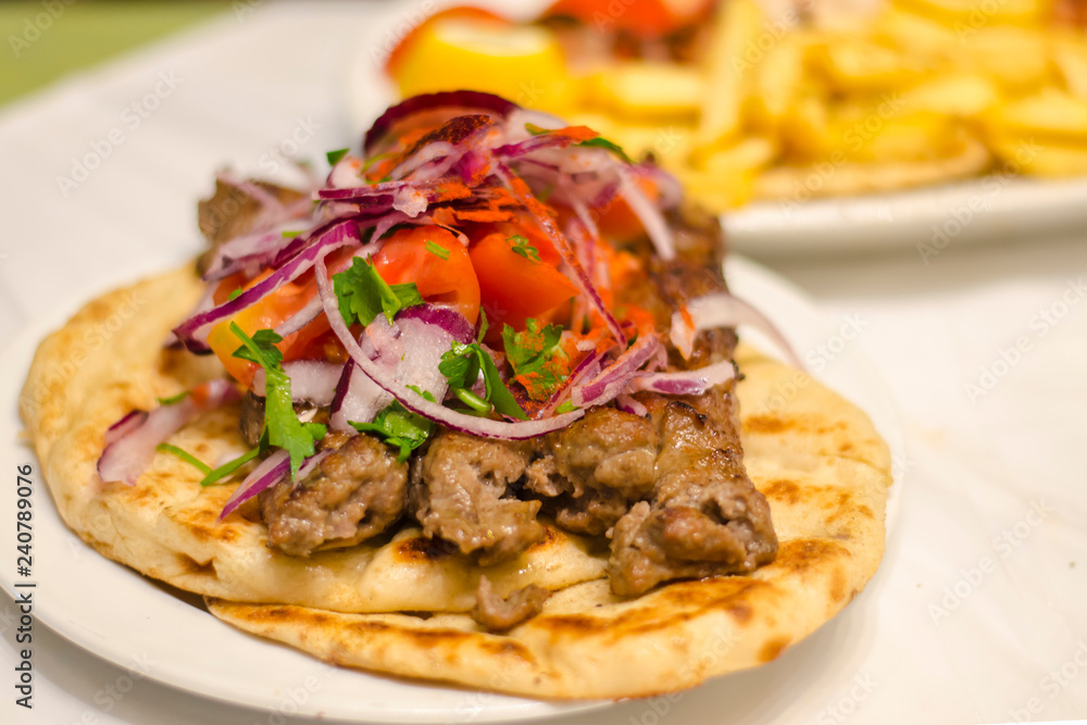 Greek kebab on pita with onions, tomatoes. Traditional Greek Cuisine Greek kebab on pita with onions, tomatoes. Traditional Greek Cuisine