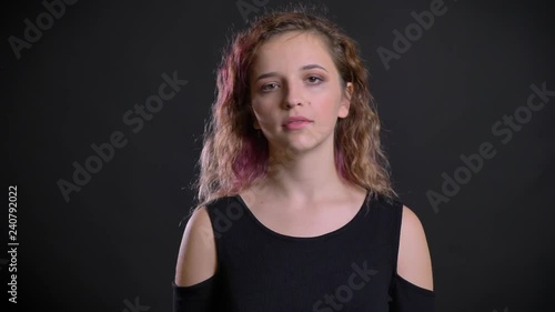 Portrait of young caucasian girl with pink hair negatively turning her head into camera on black background. photo